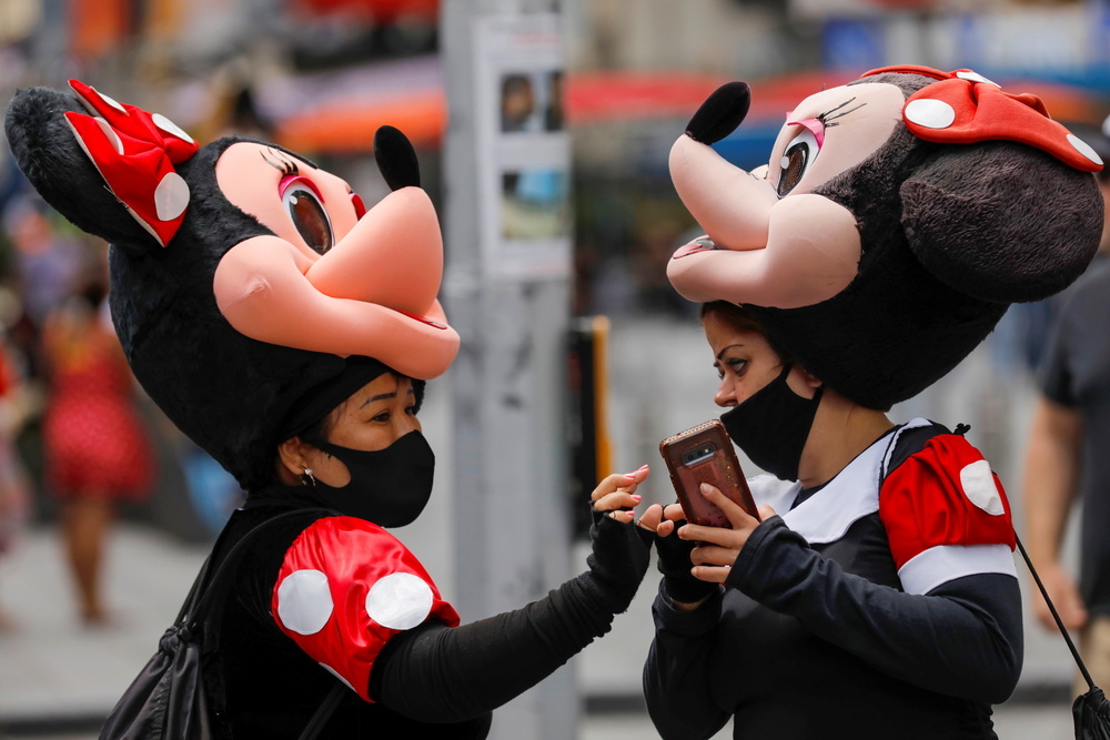 Dos mujeres con mascarilla disfrazadas de Minnie Mouse en los alrededores de Times Square.
